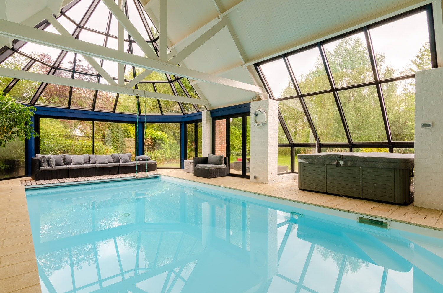 piscine intérieure sous verrière avec spa et vue sur le jardin